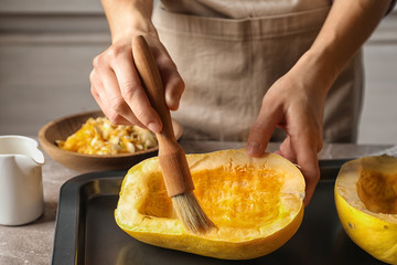 Woman preparing spaghetti squash on table, closeup