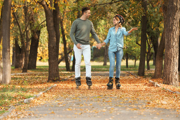 Fototapeta premium Young couple roller skating in autumn park