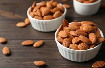 Tasty organic almond nuts in bowls on table
