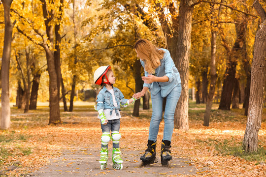 Mother And Her Daughter Roller Skating In Autumn Park