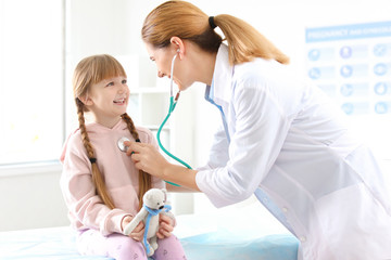 Children's doctor examining little girl in hospital