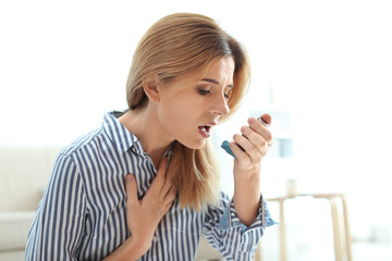 Woman using asthma inhaler at home. Health care