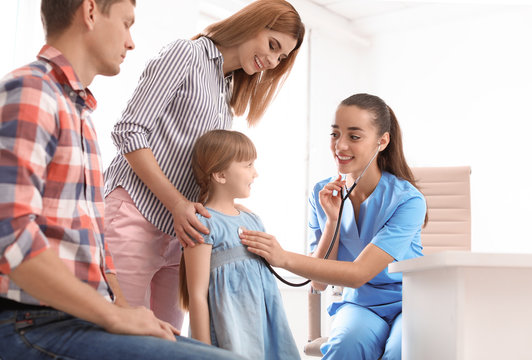 Children's doctor examining little girl near parents in hospital