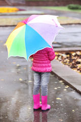 Obraz premium Little girl with umbrella taking autumn walk in city on rainy day