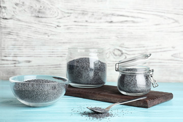 Poppy seeds in different dishware on wooden table