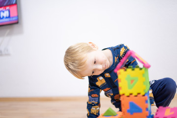 Preschooler child playing with colorful toy blocks. Kid playing with educational wooden toys.