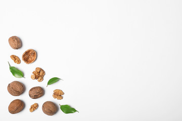 Walnuts with leaves on white background, flat lay with space for text