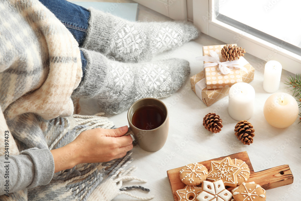 Sticker Woman relaxing with cup of hot winter drink near window. Cozy season