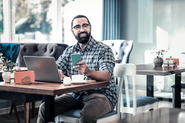 Fototapeta premium Work remotely. Successful businessman wearing squared shirt working remotely sitting in restaurant