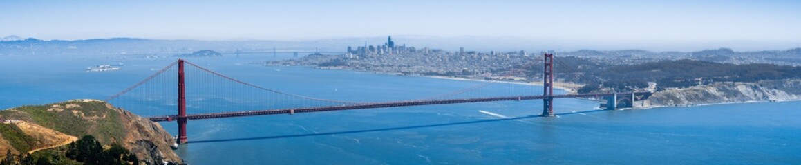Panoramic view of Golden Gate Bridge; the San Francisco skyline visible in the background;...