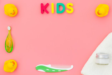 Hygiene items for the child. Bath accessories with yellow rubber duck on pink background top view copy space frame. Word KIDS