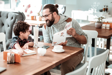 Preschool tutor. Private preschool tutor feeling involved in teaching little cute boy in cafeteria
