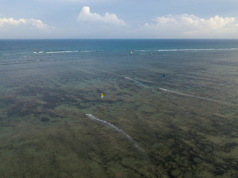 Aerial view of kiteboarding, kitesurfing. Extreme sports kitesurfing in tropical blue ocean, clear beach. Aerial views, top view from drone of kitesurfing on the waves of the beautiful sea