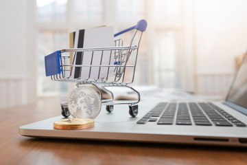 Business and finance concept,  Close up shopping cart with credit card and bitcoin on desk for E-Commerce online shopping.