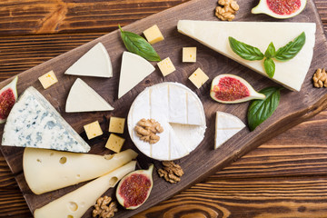 Cheeseboard with cheese brie , parmesan , camembert and dorblu . Food on wooden board