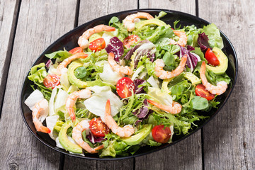 Mix of salad with shrimps , avocado and cherry tomatoes . Healthy food background