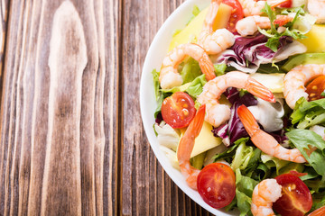 Mix of salad with shrimps , avocado and cherry tomatoes . Healthy food background