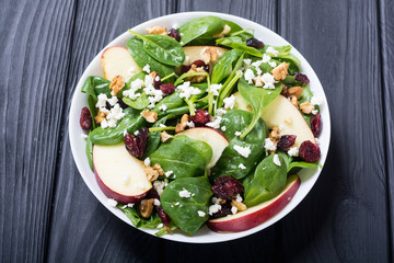 Autumn spinach salad with apple , cheese , walnut and dried cranberry . Healthy vegetarian food