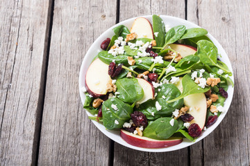 Autumn spinach salad with apple , cheese , walnut and dried cranberry . Healthy vegetarian food