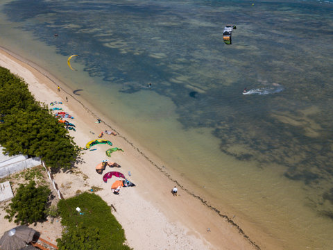 Kiteboarding, kite surf. Extreme sport kitesurfing in tropical blue ocean, clear beach. Aerial views, top view from drone of kitesurfing on the waves of the beautiful sea. Kite surfer rides the waves