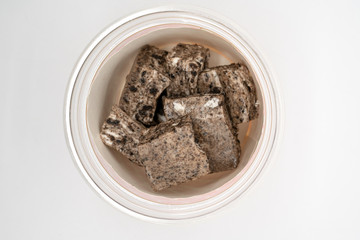 Closed up homemade chocolate marshmallow treat bar in plastic cup isolated on white