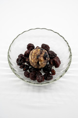 Close up healthy energy ball among dried berries in glass bowl isolated on white