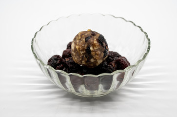 Close up healthy energy ball among dried berries in glass bowl isolated on white