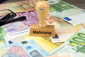 Euro Geldscheine, eine Rechnung und ein Stempel mit dem Aufdruck Mahnung