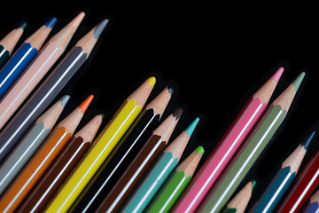 A pack of multicolored pencils on a dark background close up