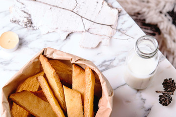 Kolakakor - swedish cookies, bottle of milk and candle and pine cone on grey marble table. Fast and easy scandinavian pastry. Cozy winter treat. Hygge. Fika