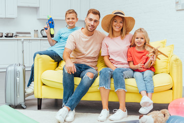 family resting on sofa after packing for summer vacation, travel concept