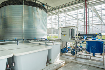 interior and equipment with pipelines and water tank in modern greenhouse