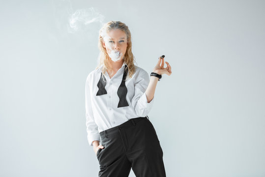 attractive stylish blonde girl smoking cigar isolated on grey