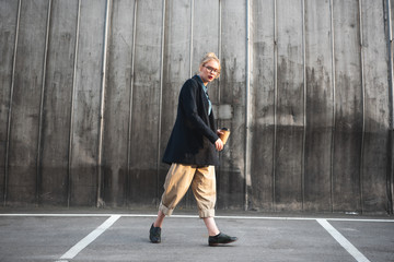 stylish girl with disposable cup of coffee walking on parking