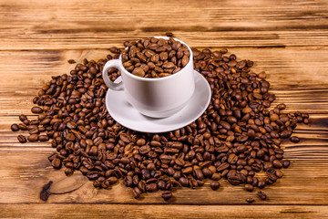 White cup filled with coffee beans on wooden table