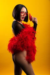 Fun, colorful portrait of pretty Asian woman wearing red feather boa and heart shaped glasses