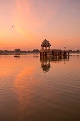 Amazing panoramic view of Gadisar or Gadi Sagar Lake with the view of historical building and temple during sunrise in Jaisalmer, India.