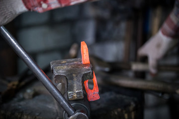 Workspace of blacksmith. Blacksmith working with red hot metal workpiece of new hammer in the vise