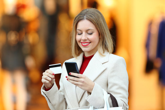 Happy woman buying online with credit card in winter