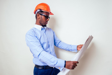 architect designer black man African American holding paper drawing template.happy african builder painting house,businessman wears a helmet hard hat.young guy is painting sketch construction plan