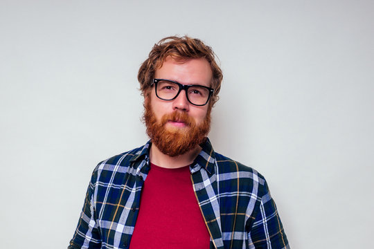 Close Up Portrait Of Redhead Bearded Male With Red Head And Stylish Glasses Green Tartan Shirt And Red Cotton T-shirt On White Background In Studio.