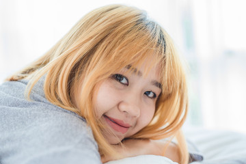 Portrait beautiful young Asian woman on bed at home in the morning. Cheerful Asian woman wearing a comfortable sweater and smiling on her bed. Relaxing room. lifestyle asia woman at home concept.