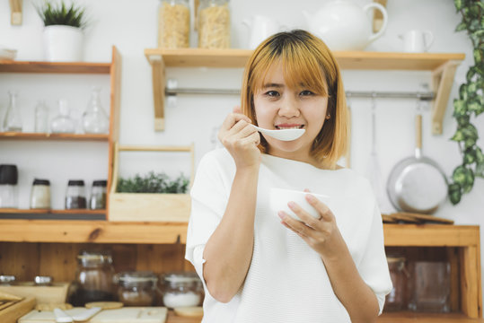 Asian woman holding bowl of warming vegetable pumpkin cream soup in her kitchen at home, female enjoy healthy lots of nutrition food. Lifestyle women relax and cooking in kitchen at home concept.