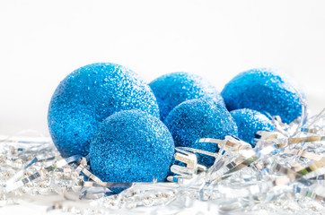 Christmas still life on a white background, including blue Christmas decorations and silver tinsel and beads.