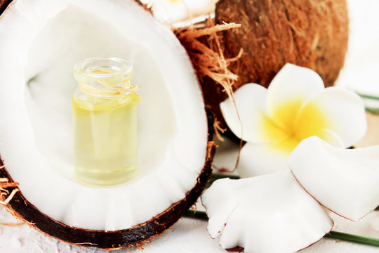 Bottle of coconut oil in open nut with fresh white fruity pulp, natural beauty treatment skincare