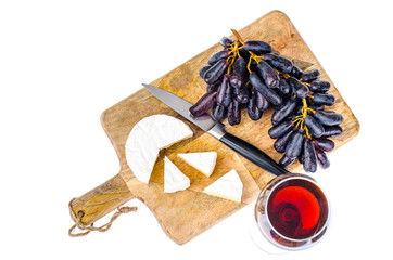 Camembert cheese with black grapes on wooden board