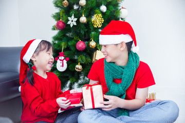 Obraz na płótnie Canvas Young asian sibling,brother and sister holding present boxes and smiling together at home with Christmas decoration
