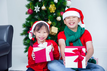 Young asian sibling,brother and sister holding present boxes and smiling together at home with Christmas decoration