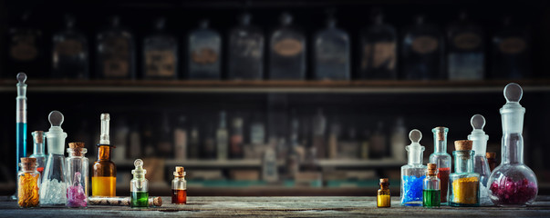 Vintage medications in small bottles on wood desk. Old medical, chemistry and pharmacy history concept background. Retro style. - obrazy, fototapety, plakaty