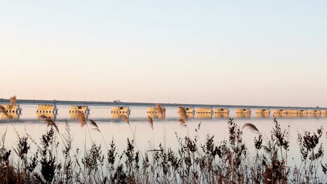 Low water bridge from Sedanka to the De Friz peninsula across the Amur Bay of Primorsky Krai Russia against the background of a red sunset sky. Far Eastern landscape. Soothing country scene.